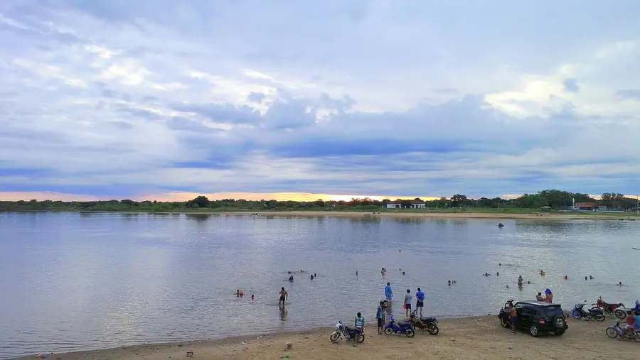 Gente en una playa de arena a orillas del río Paraguay al caer la tarde